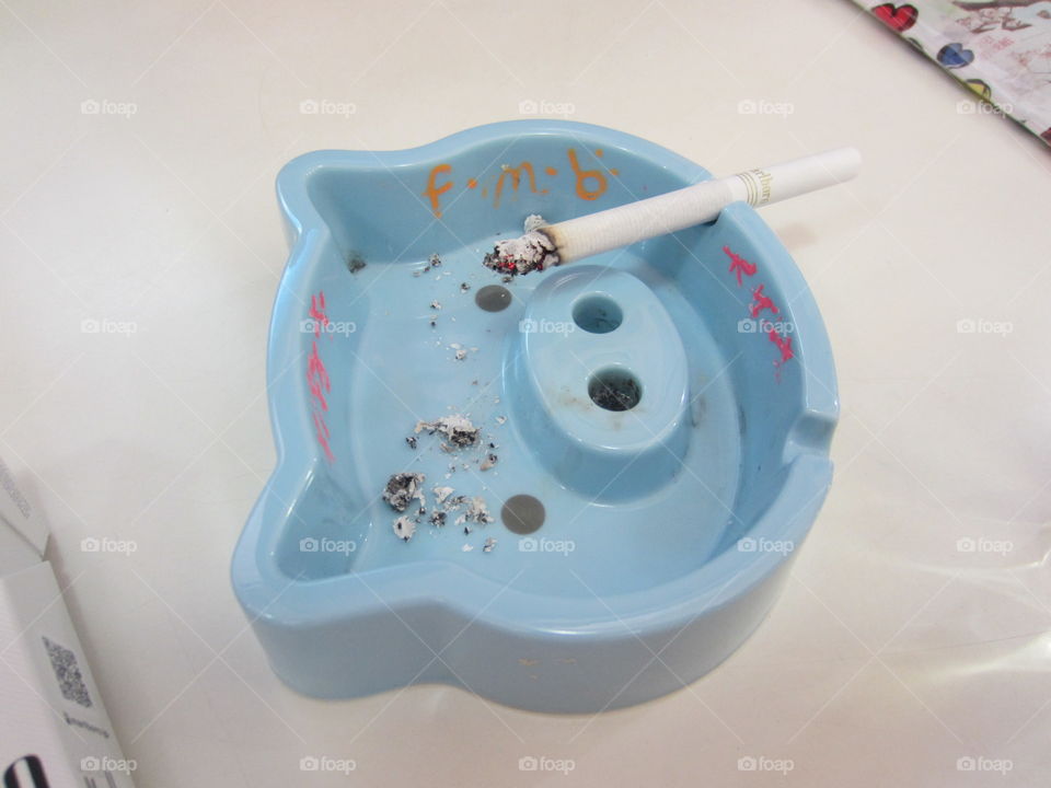cute, blue pig ashtray with lit cigarette