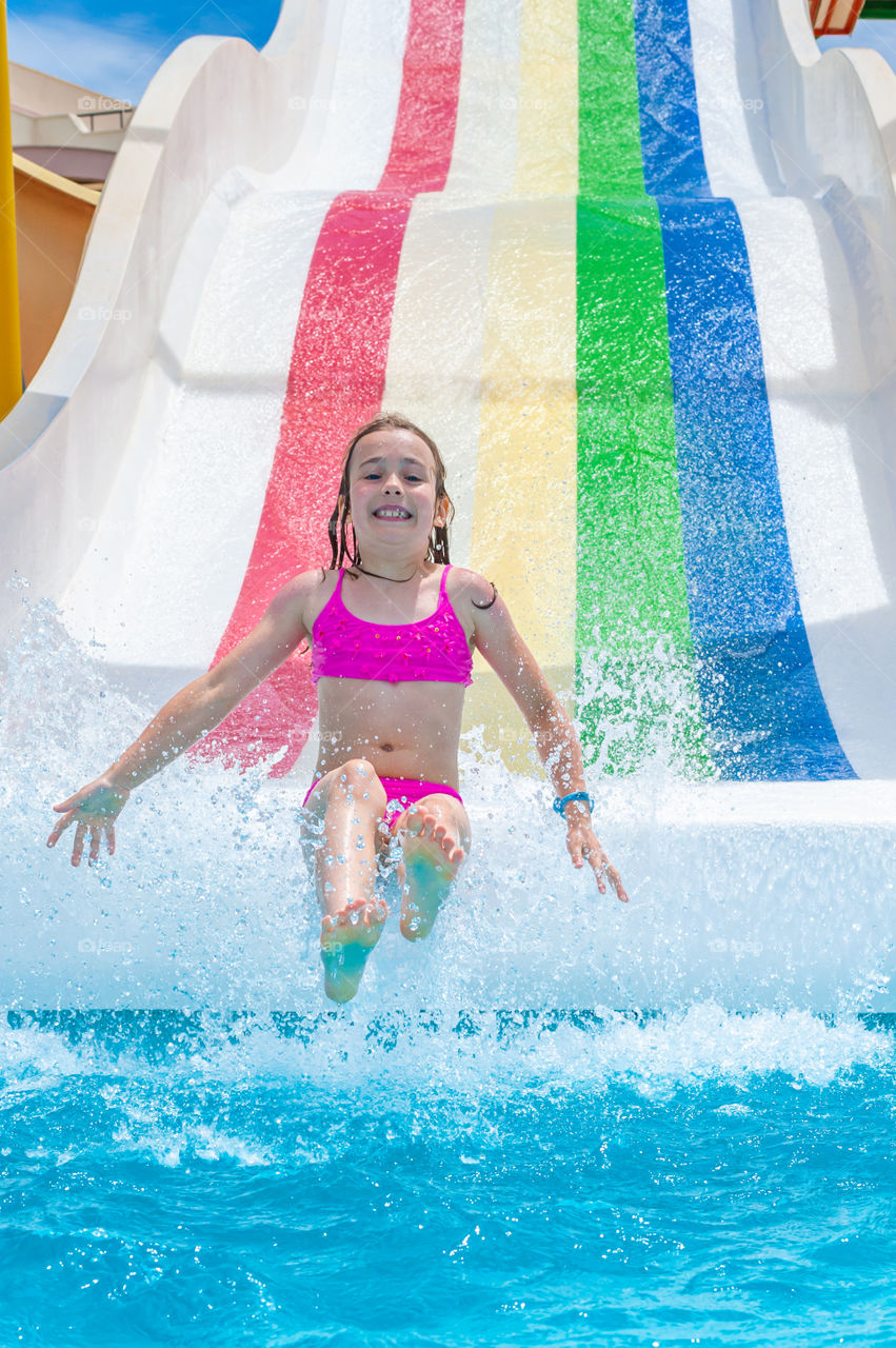 Young girl on rainbow water slide.