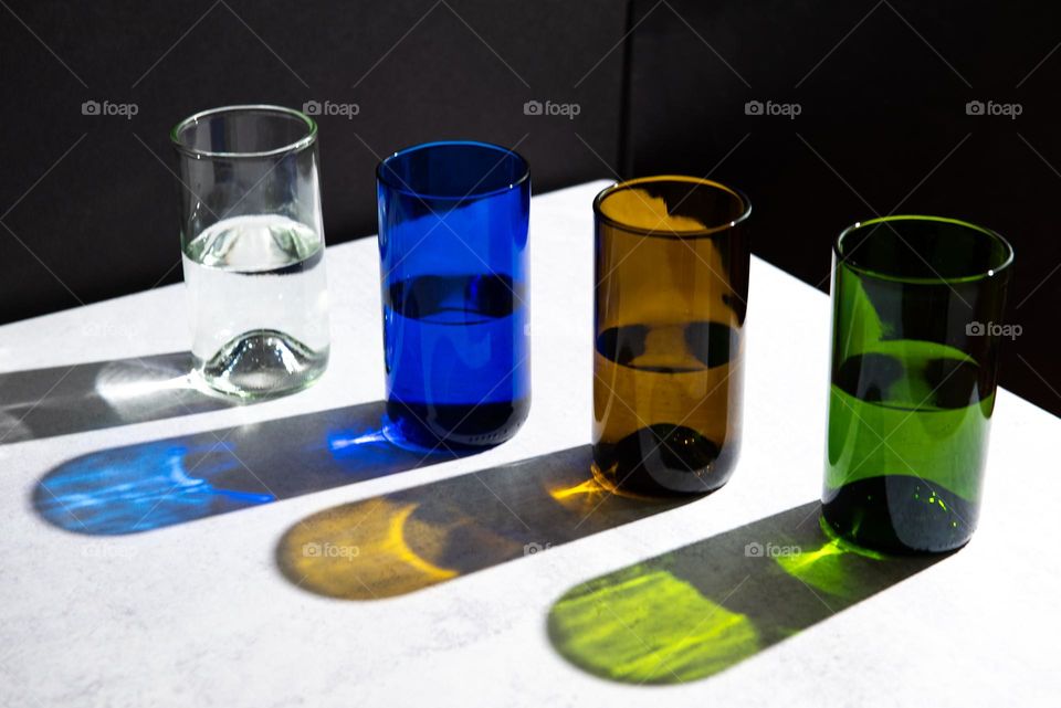Row of assorted colored glasses with hard light reflections 
