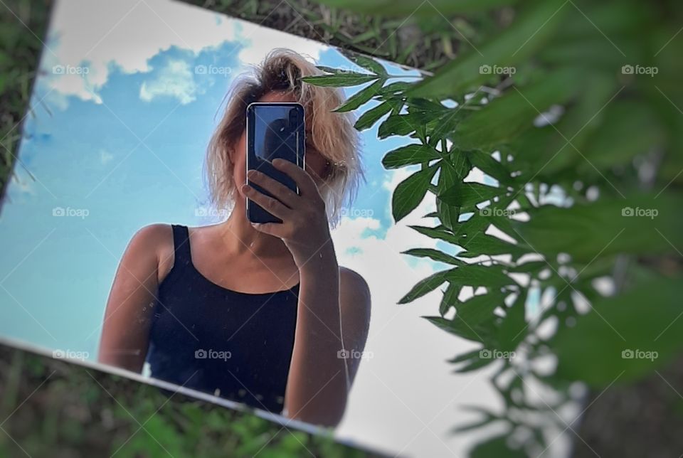 девушка в отражении зеркала на фоне голубого неба