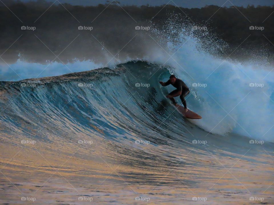 Surfer in a barrel wave at sunset