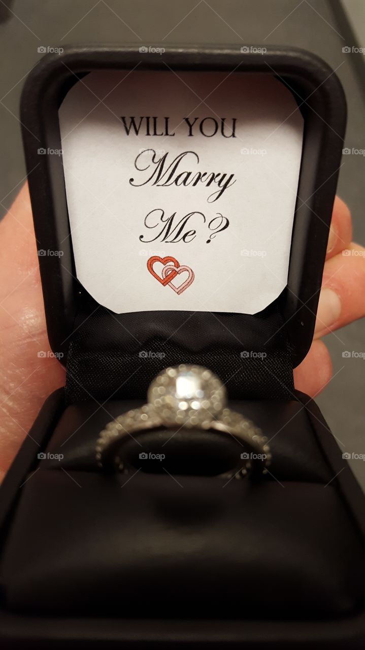 Popping the big question by presenting a diamond ring and a sentiment of love.