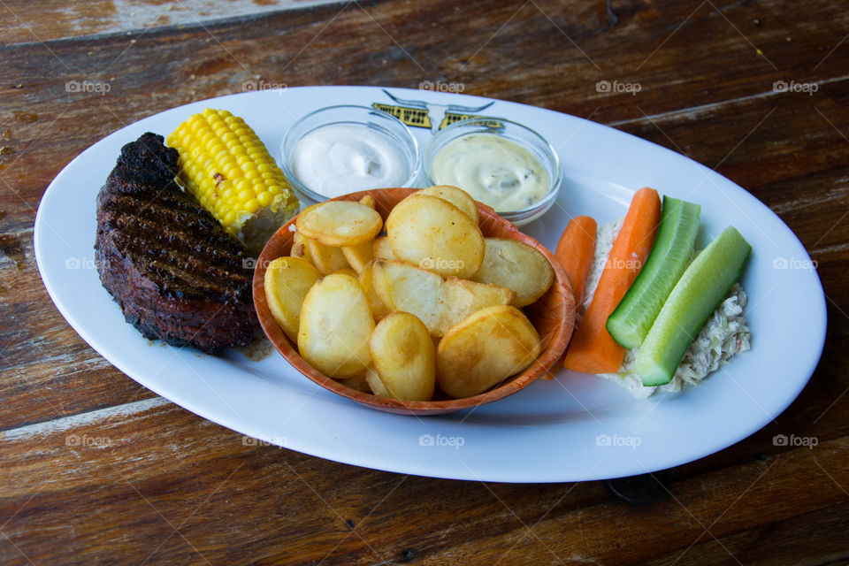 Grilled beef with potatoes and coleslaw.