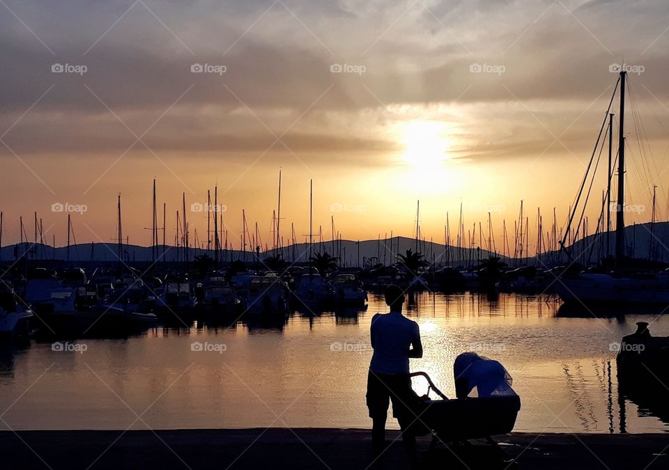 silhouette of mom with baby, in front of sea sunset