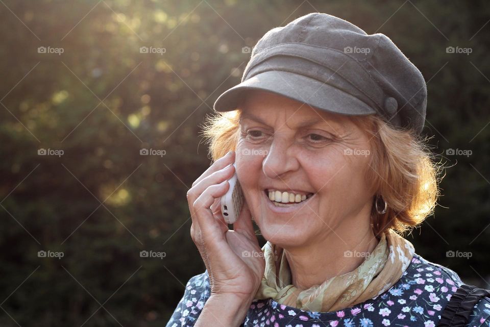 Elderly woman talking on phone outdoors