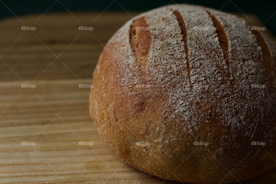 A freshly baked round loaf of sourdough bread on a wooden surface