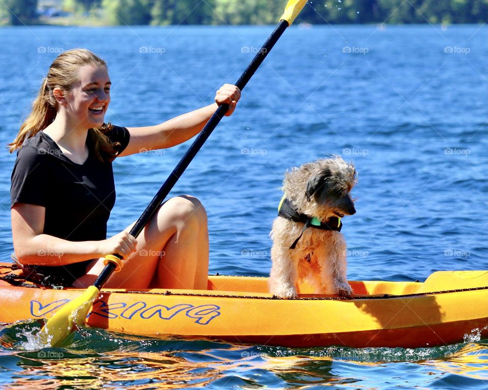 A young girl and her dog enjoy kayaking on a sunny day at American Lake in Washington State 