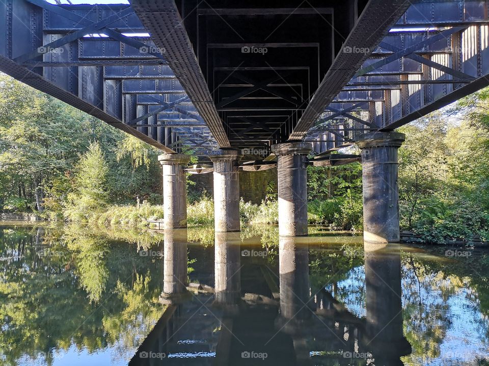 Reflections in the water under a bridge