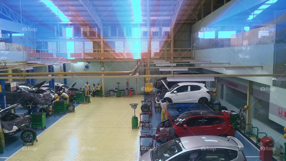 car repair shop building, official vehicle repair shop room, complete workshop equipment, from oil change, spooring and balancing, general check up, to repainting the body, the light source in the workshop room is natural form tranparent roof of the