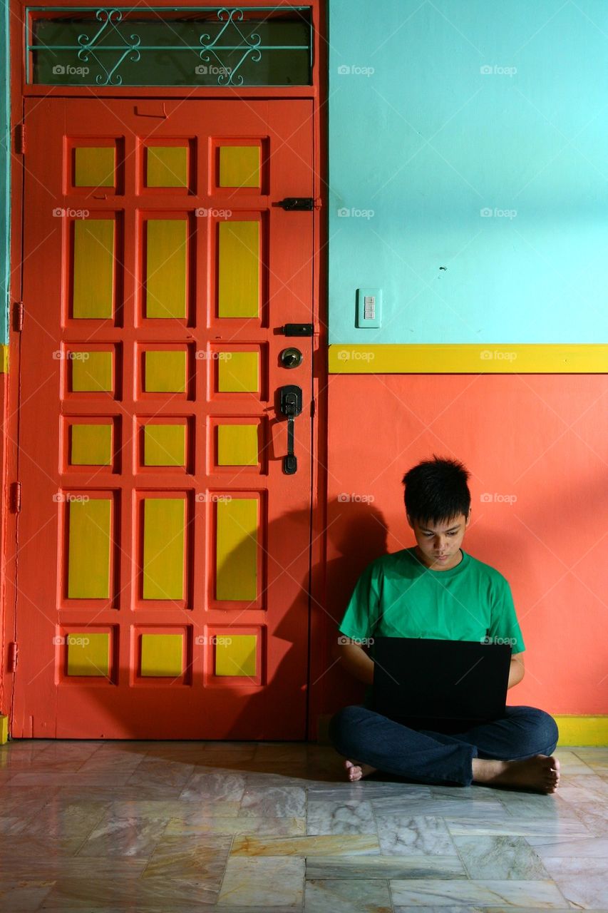 young asian teen with a laptop computer in a living room