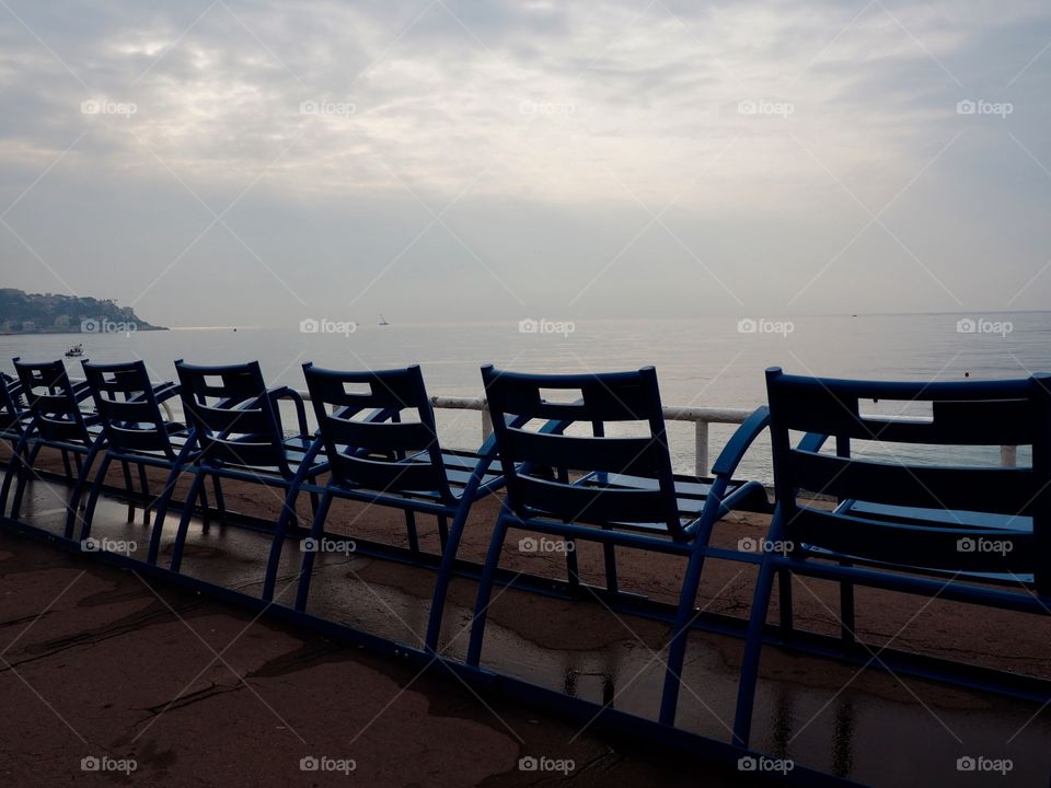 Iconic blue chairs on the Promenade des Anglais overlooking the sea.