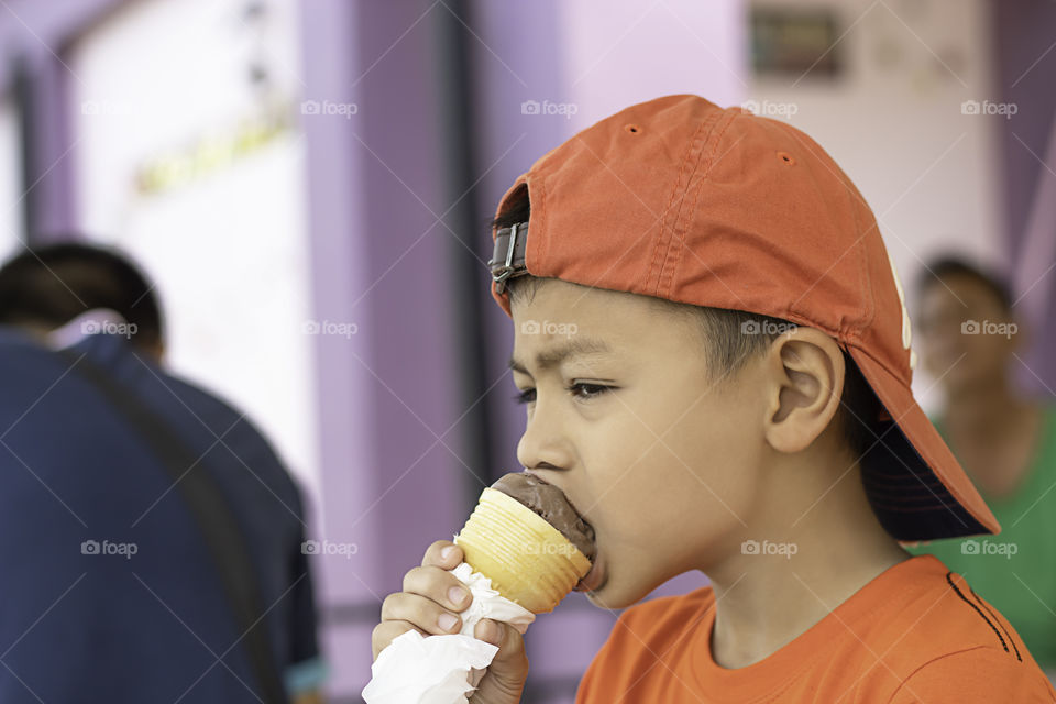 Asian boy holding the ice cream eating.