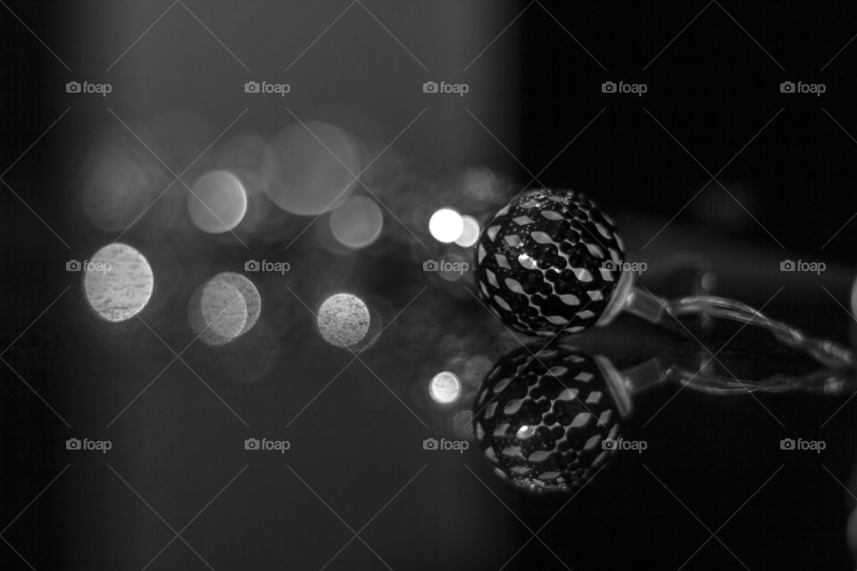 A black and white portrait of a chaine of ornament lights. the ones in the back create nice round bokeh balls.