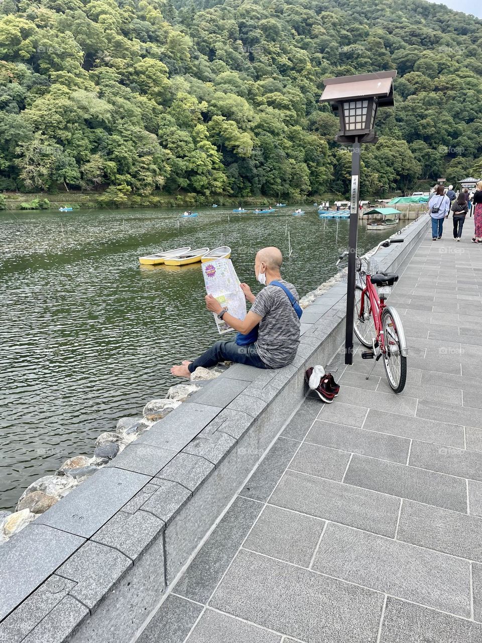 Taking a break from cycling and reading the newspaper on the river in Kyoto, Japan