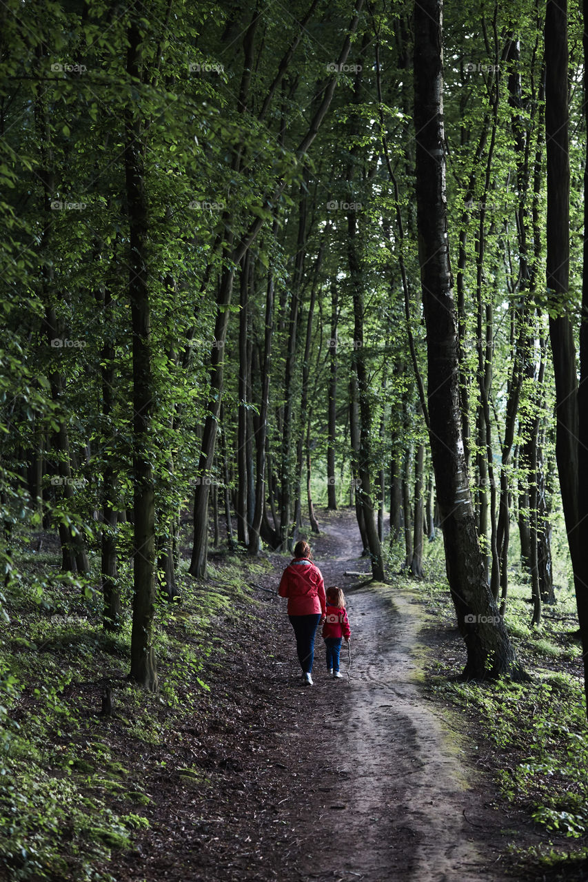 Mother with her little daughter walking through the forest. Spending leisure time, vacation on wandering in forests, close to nature