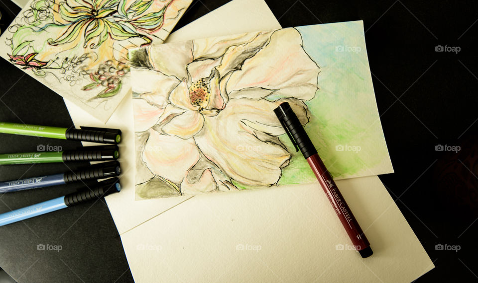 High angle view Faber-Castell PITT artist pens on desk with watercolor style painting sketch using Faber-Castell pens high angle view of spring flowers on sketch books 