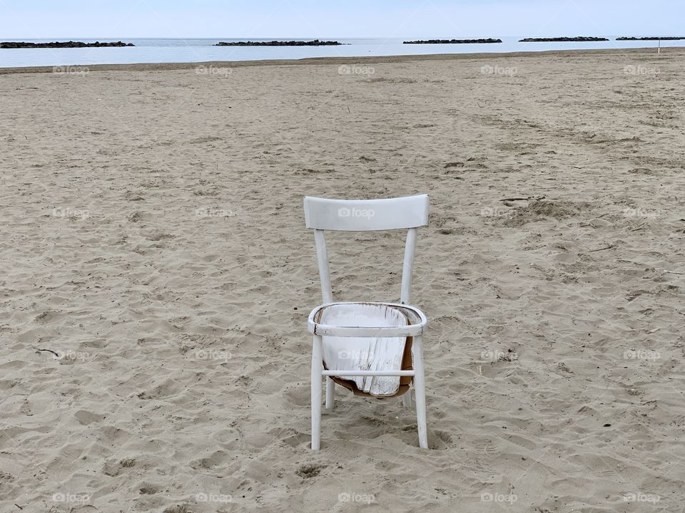 Empy beach with an abandoned and broken wooden chair 