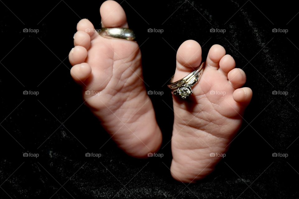 Baby feet with wedding rings in his toes