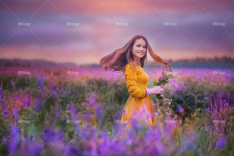 Portrait of young beautiful woman in violet meadow at summer evening 