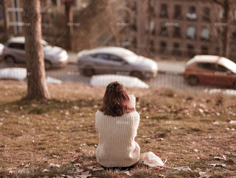 sitting in the autumn sun reading a book in the park with golden leaves around