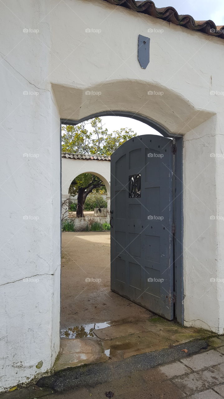 a side entrance from an alley into the back courtyard of an old adobe mission style building in Monterey, Ca