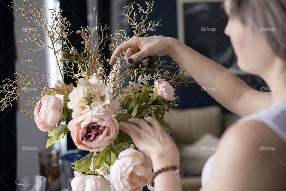 Women adjusting flowers in vase