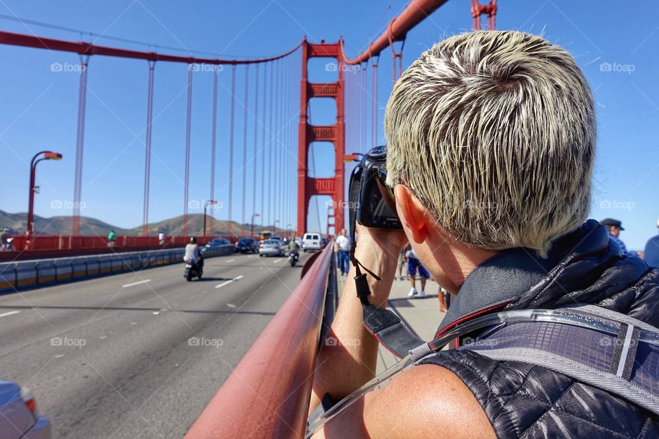 Woman photographer taking photos of the Golden Gate Bridge in San Francisco, CA. 
