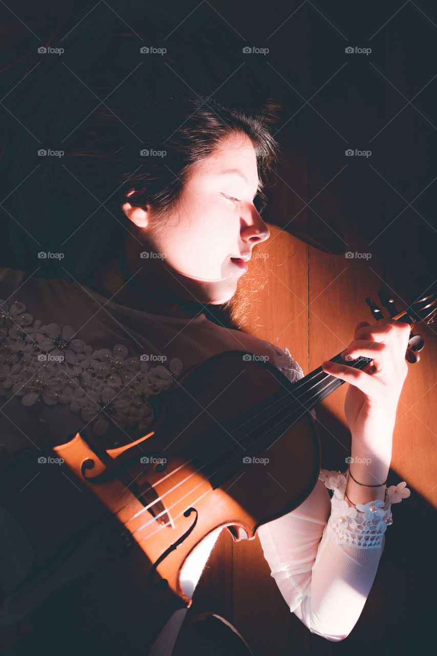 Girl holding a violin in the house