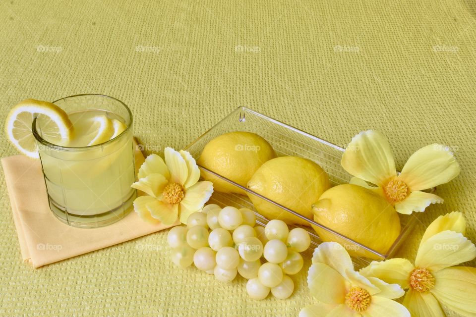 Yellow monochrome still life with lemons, lemonade, and white grapes