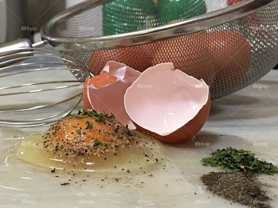 Farm fresh cracked brown egg raw on kitchen countertop, kitchen utensils 