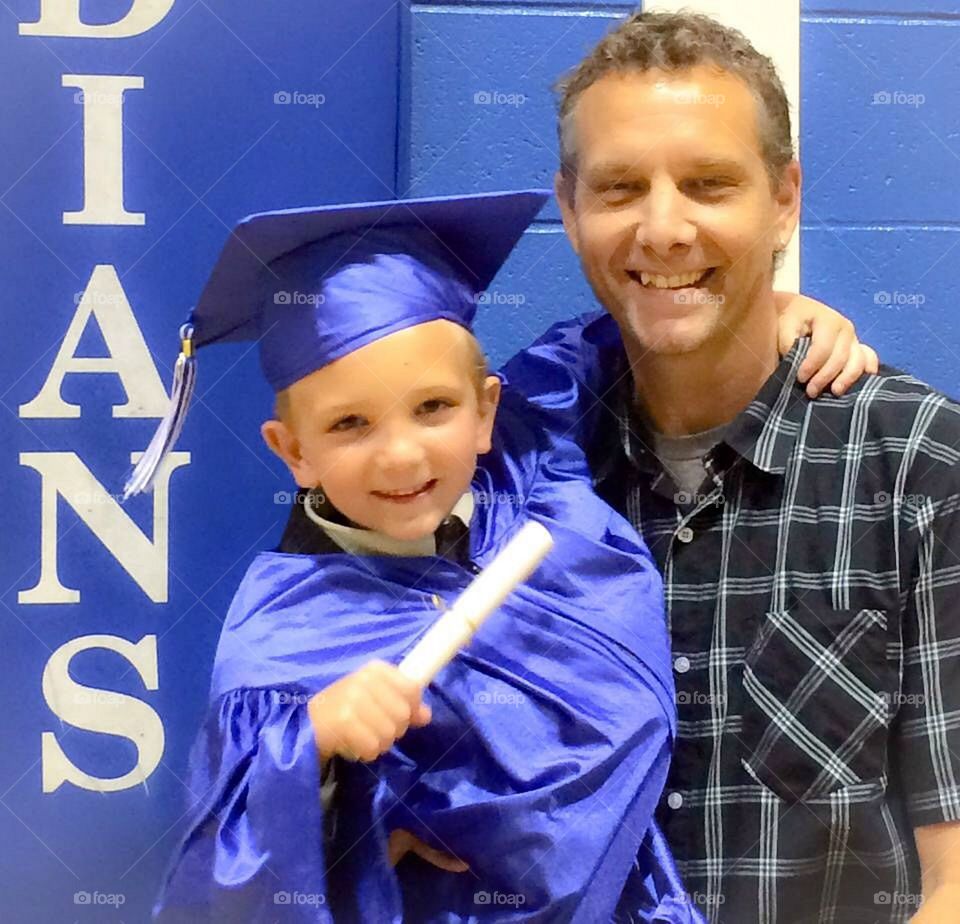 Father carrying his boy wearing graduation gown