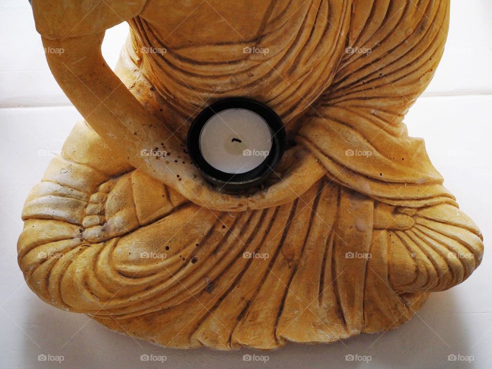 Yellow Buddha with a waxine light, buddha statue, Boeddha of stone, meditative image