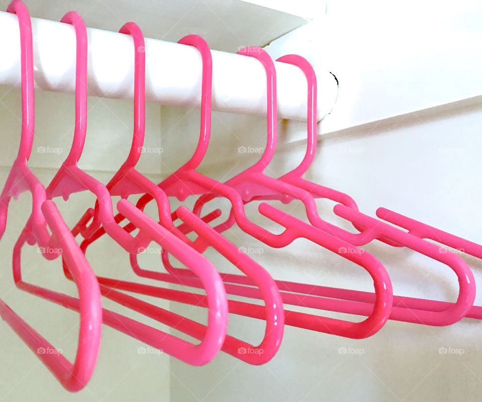 Pink plastic hangers hanging in home