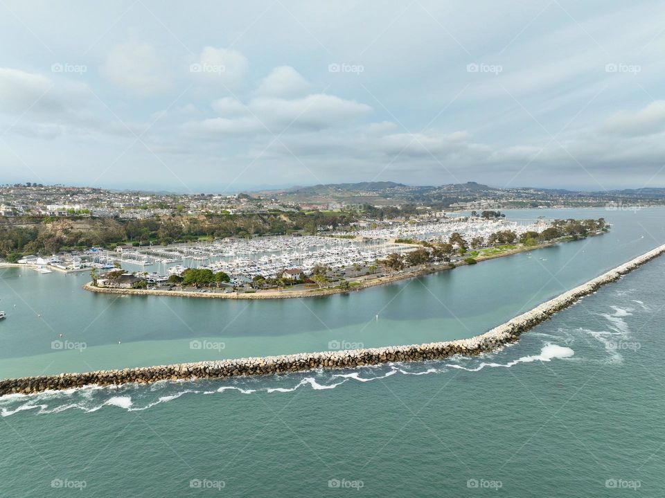 The sun finds its way through the marine layer in beautiful Southern California as the ocean meets the breaker in Dana Point 