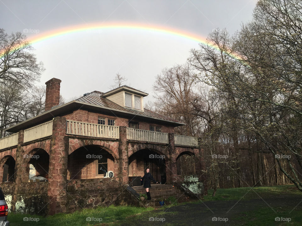 A girl shines under an immaculate rainbow above her 4th generation, Tuscan-style home in rural Virginia