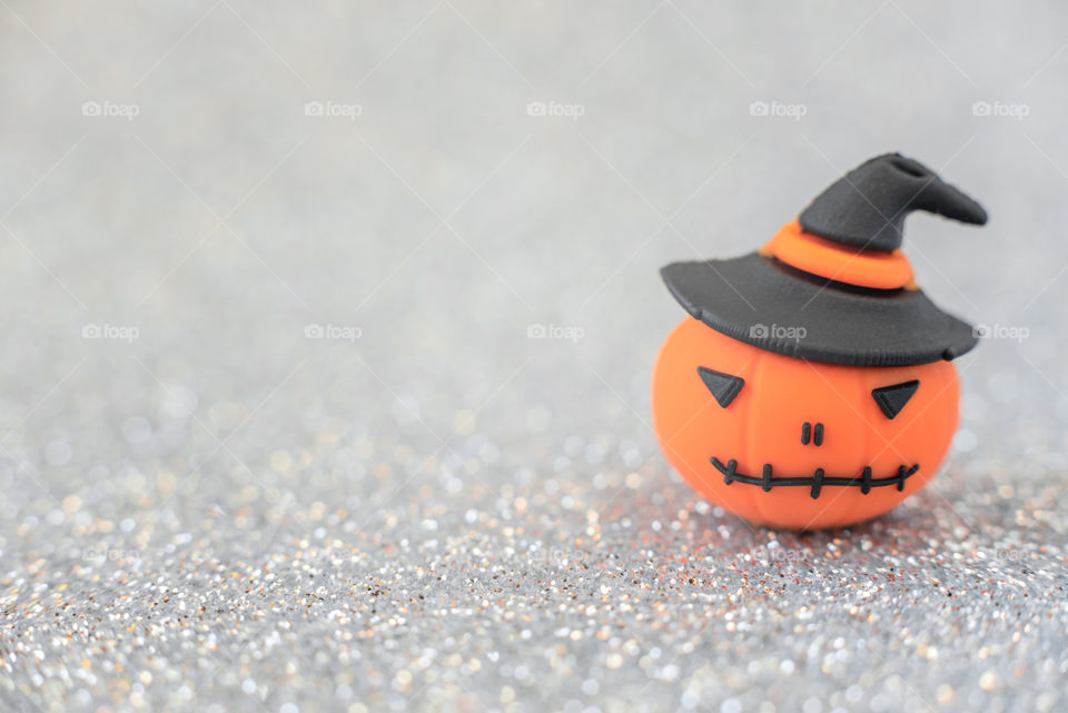 Orange decorative pumpkin on silver blurred background. Halloween, minimalism concept. Greeting, invitation card. Copy space for the text.  