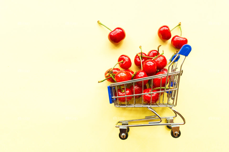 Fresh cherries lying in mini grocery cart