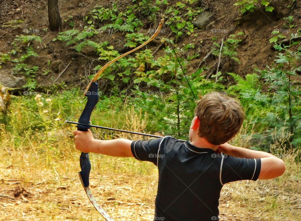 Practicing Archery. Young Boy Shooting A Bow And Arrow