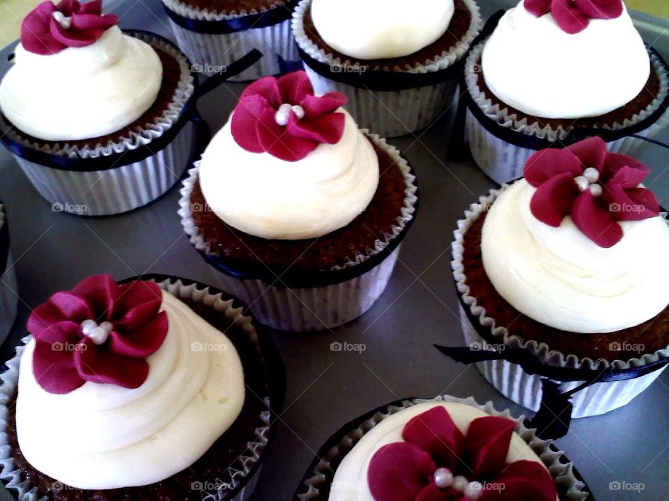 Delicious chocolate cupcakes with vanilla icing with a piped spring flower.