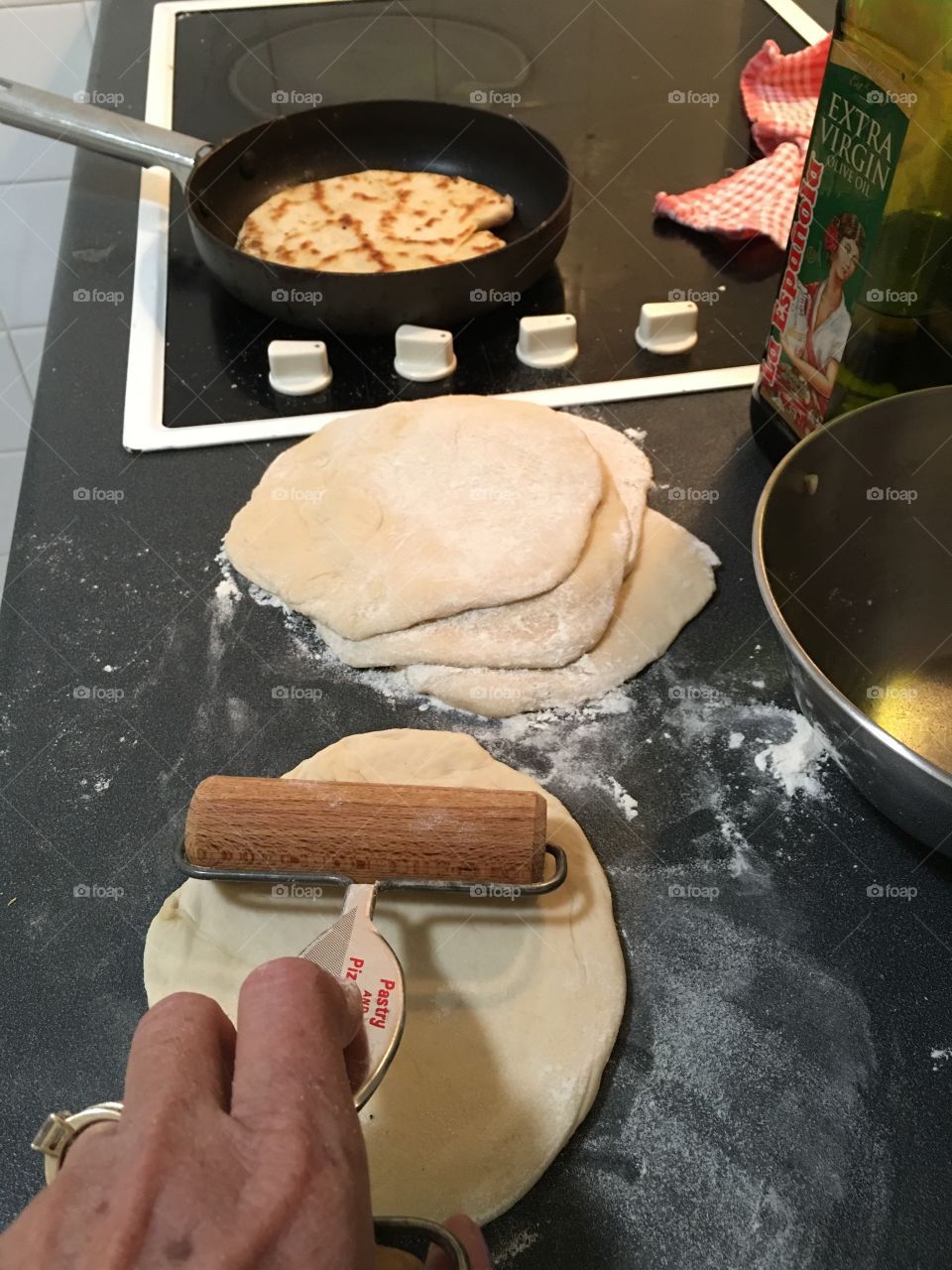 Preparing homemade pita bread, rolling out the dough into circles and quickly into the pan