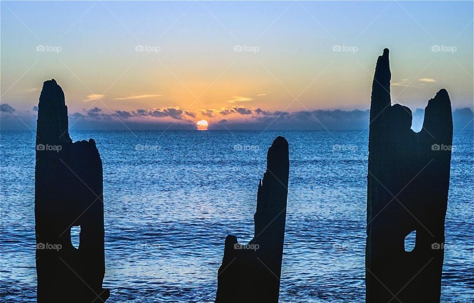 The winter sunrise silhouettes the wooden sea defences on Winchelsea beach, UK 