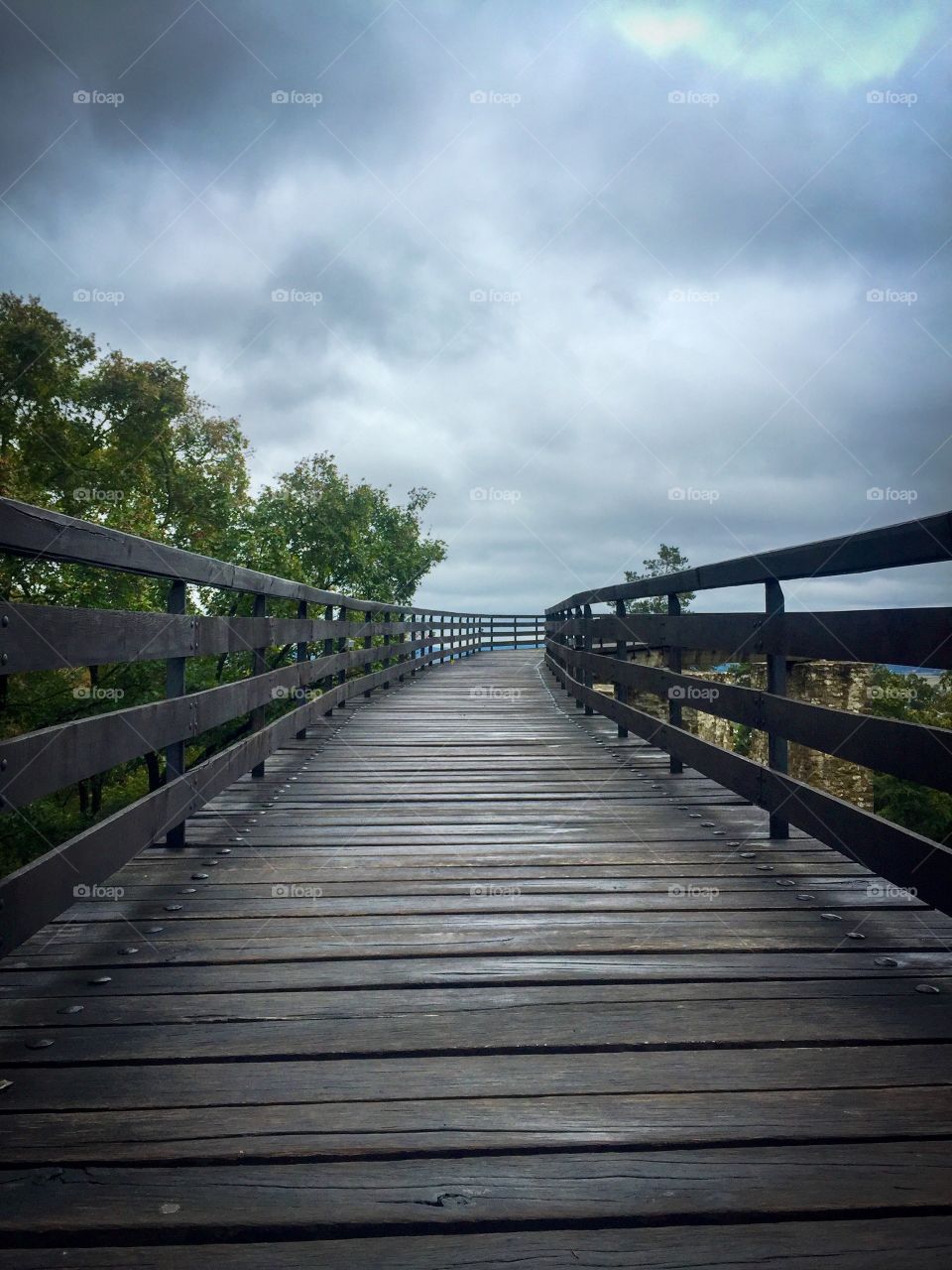 Suspended wooden bridge with grey storm clouds above