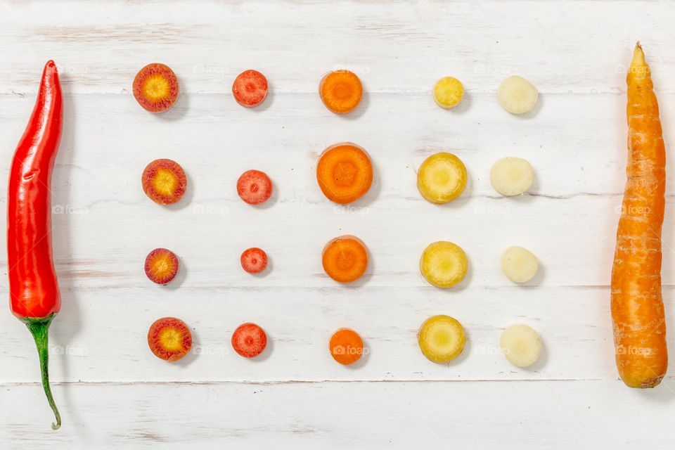 Photo of Red Pepper And Carrot Flatlay

 Spicy red peppercorns with whole and sliced ​​carrots look colorful and delicious on this kitchen's white cutting board.