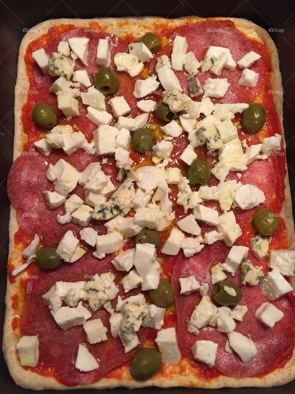 Pizza with salami, cheeses and white olives