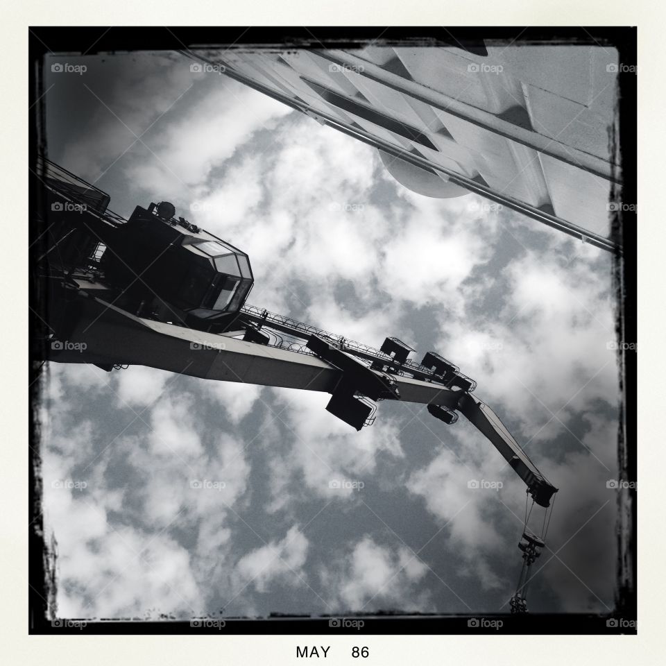 Looking up at a crane against the cloudy sky.