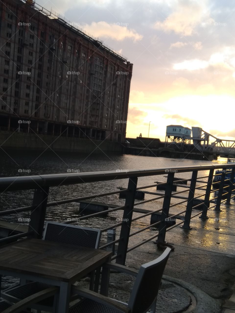 Taken on the docks at sunset: the reflection of the water and the light hitting the puddles with the buildings in the background added depth.