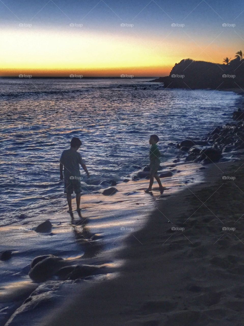 Silhouettes of children on the beach at dusk 