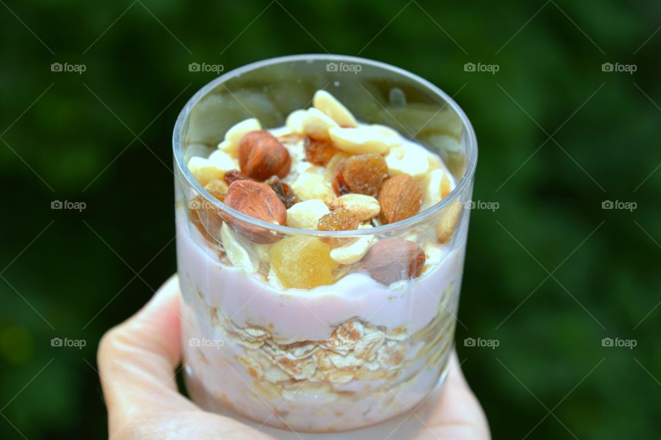 tasty healthy summer  food oat with nuts in the hand green background