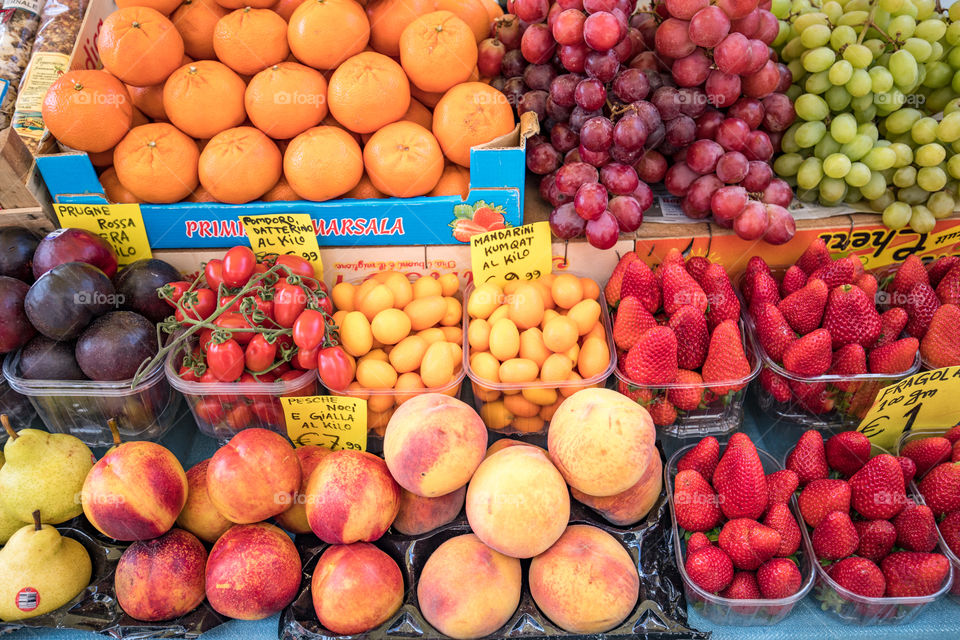Variety of colorful fresh juicy fruits in the baskets on  grocery market. Oranges, peaches, strawberries, pears, nectarines, mandarins, kum quats, tomatoes, plums, green grape, red grape.