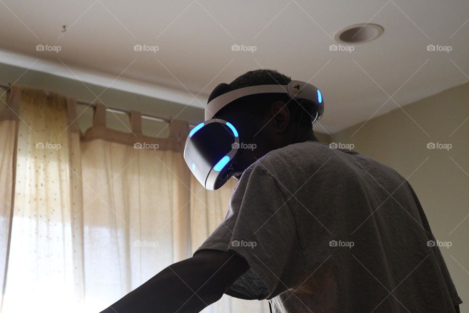 A young man engages in a session of virtual reality gaming in the living room of his home.